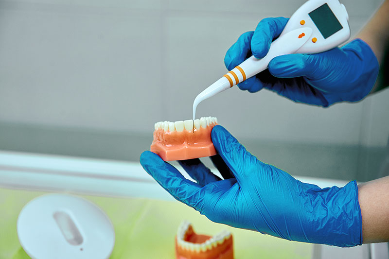 dentist-holding-teeth-model-denture-and-periodonta-VSYZJTE