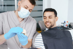 male dentist showing patient the artificial dentur 2021 09 04 06 37 39 utc 1